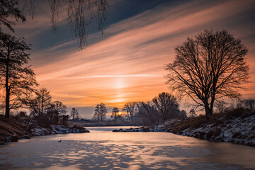 Krajobraz zimowy. Widok ze wschodem słońca i zimowy poranek nad rzeką. Zamrożona rzeka. Świtanie w zimowej scenerii. Mroźny poranek. Tło natury.	