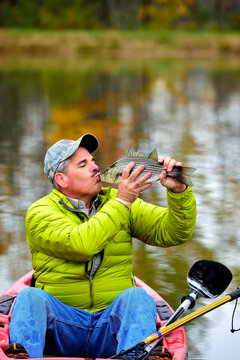 Close-up Of A Man Kissing A Fish In A Kayak