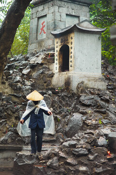 A caretaker wearing a traditional Non La hat sweeping a shrine at the Hoan Kiem Lake in Vietnam.
