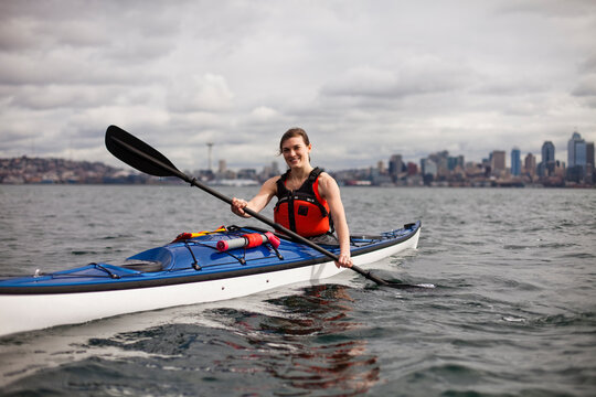 A young girl kayaks on a cloudy day in the Puget Sound off the coast of downtown Seattle.