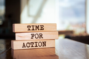 Wooden blocks form the words 'Time For Action' on blur background.