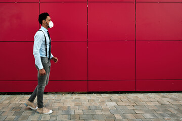 Man with face mask walking outdoors on the street.