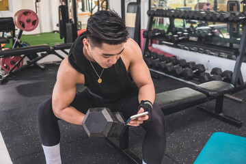 A distracted man checking his social media feed on his cellphone while doing a set of seated concentration dumbbell curls at the gym.
