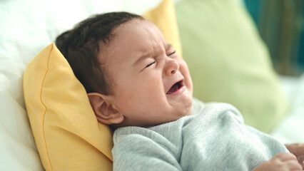 Adorable hispanic baby lying on bed crying at bedroom