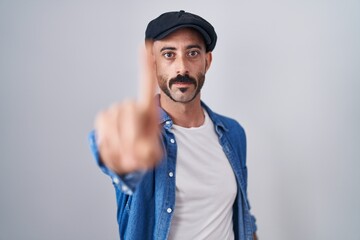 Hispanic man with beard standing over isolated background pointing with finger up and angry expression, showing no gesture