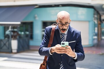 Young hispanic man executive using smartphone at street