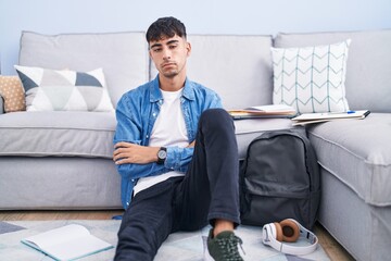 Young hispanic man sitting on the floor studying for university looking sleepy and tired, exhausted for fatigue and hangover, lazy eyes in the morning.