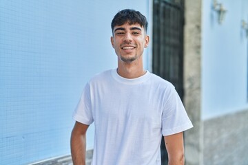 Young hispanic man smiling confident standing at street