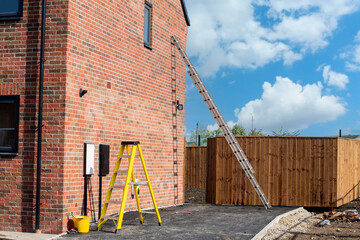 Aluminium ladder leaned against brick wall