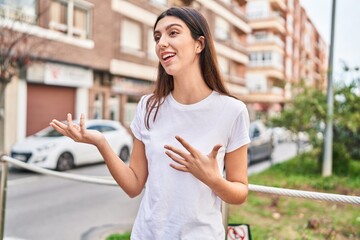 Young beautiful hispanic woman looking to the side speaking at street