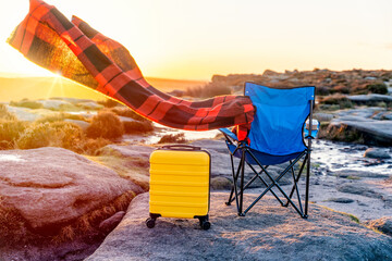 Blue beach chair, yellow  Suitcase, orange scarf in  the national park Peak District at sunrise....
