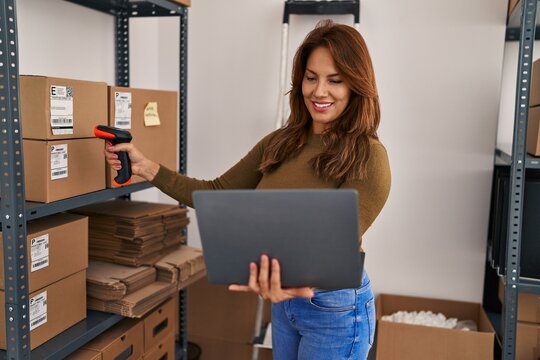 Young latin woman business worker scanning package using barcode reader at office