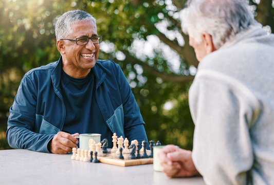 Chess, nature and retirement with senior friends playing a boardgame while bonding outdoor during summer. Park, strategy and game with a mature man and friend thinking about the mental challenge