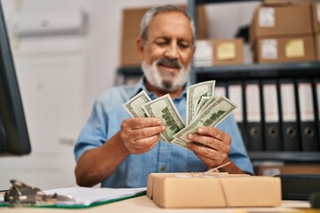 Senior grey-haired man ecommerce business worker counting dollars at office