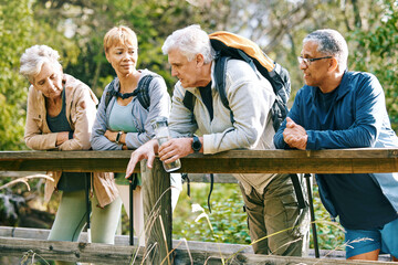 Elderly, people hiking and happy in park with fitness outdoor, relax on bridge while trekking in nature together. Health, wellness and hiker group, sport and active lifestyle motivation with cardio.