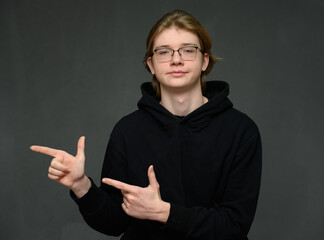 Caucasian guy portrait showing fingers to the side on a gray background looking at the camera - 559124877