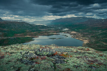 Mountain landscape with lake Nedre Leirungen from above the hike to Knutshoe summit in Jotunheimen National Park in Norway, mountains of Besseggen in background