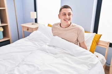 Young hispanic man smiling confident sitting on bed at bedroom