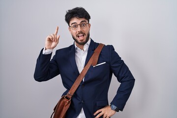 Hispanic man with beard wearing business clothes pointing finger up with successful idea. exited and happy. number one.