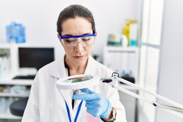 Young hispanic woman wearing scientist uniform working at laboratory