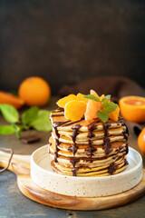 Celebrating Pancake day, healthy american breakfast. Delicious bananas pancakes with chocolate and red oranges on rustic table. Copy space.