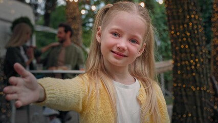 Portrait cute little child outdoors camping small kid girl baby schoolgirl daughter waving hand inviting welcome gesture come here invite Caucasian parents mom and dad near van talking on background