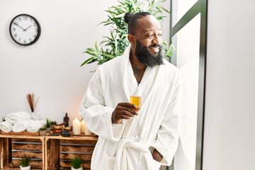 Young african american man smiling confident drinking champagne at beauty center