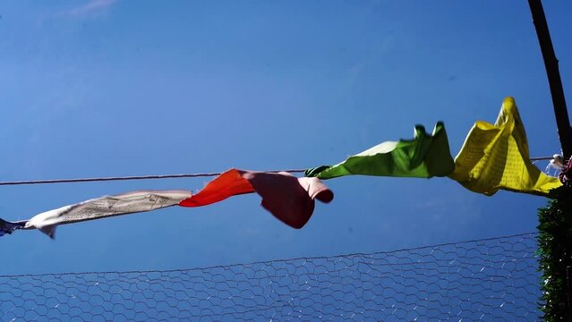 slow motion sacred religious multicolored prayer flags against blue sky moving in the wind showing a bhuddist prayer incantation common in hill stations in Himachal Pradesh India
