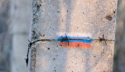 Painted Russia flag on the concrete pole with barbed wire over it.