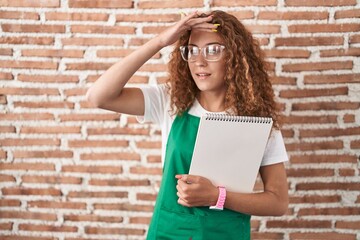 Young caucasian woman holding art notebook very happy and smiling looking far away with hand over head. searching concept.