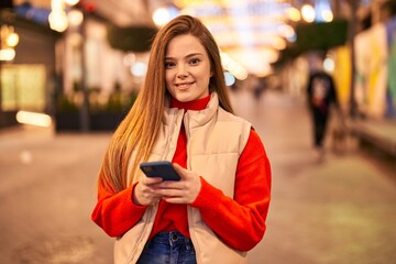 Young blonde woman smiling confident using smartphone at street