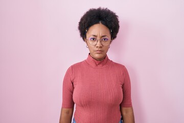 Beautiful african woman with curly hair standing over pink background skeptic and nervous, frowning upset because of problem. negative person.