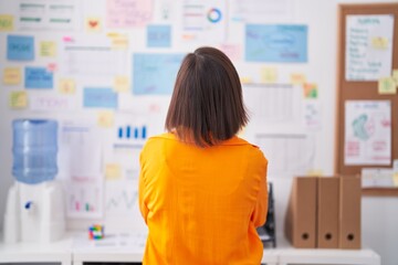 Middle age woman business worker reading paperwork on wall at office