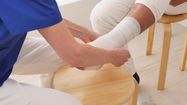 足に包帯を巻く医師　顔無し