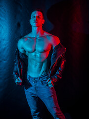 Muscular bodybuilder opening leather jacket on naked muscle torso