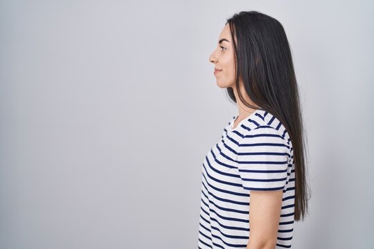 Young brunette woman wearing striped t shirt looking to side, relax profile pose with natural face and confident smile.