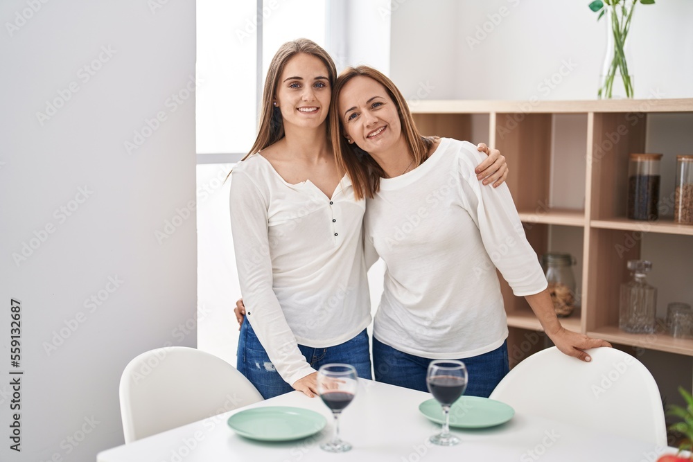 Wall mural two women mother and daughter hugging each other standing at home