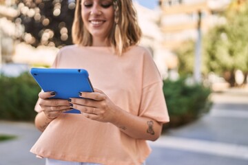 Young hispanic woman smiling confident using touchpad at park