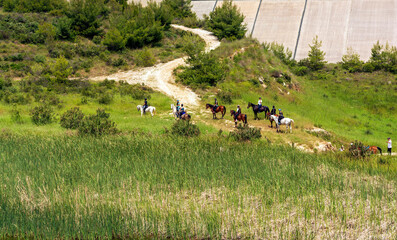 View of Rapentosa dam lake with beautiful horses and young girls equestrians, Greece