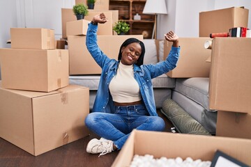 African american woman stretching arms sitting on floor at new home