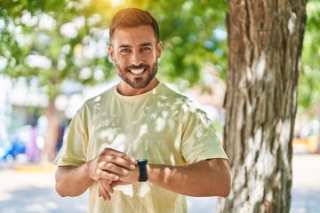 Obraz premium Young hispanic man smiling confident looking watch at park