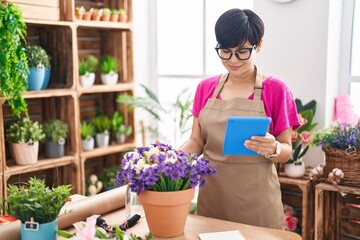 Middle age chinese woman florist smiling confident using touchpad at flower shop