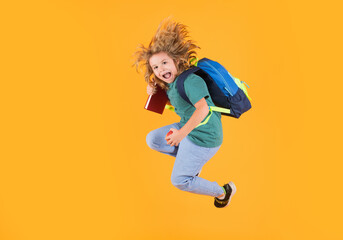 Fototapeta na wymiar Full length of excited kid jumping. Back to school. Full length body of little school kid jumping having fun isolated yellow color background. Crazy school boy jump.