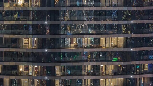 Outside view of windows in apartments of a high class building at night timelapse. Glowing yellow lights in skyscraper