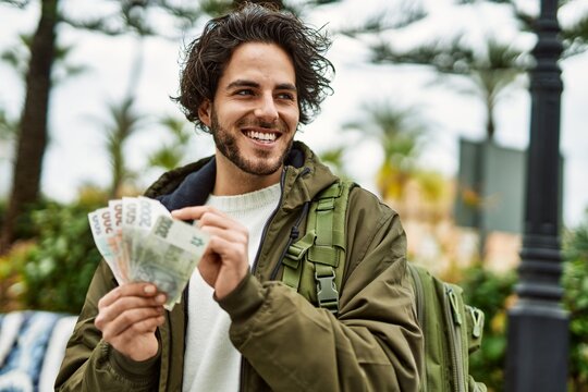 Handsome hispanic man holding czech crown banknotes at the city
