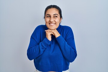 Young hispanic woman standing over isolated background laughing nervous and excited with hands on...