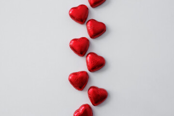 Love and Valentine's day background - close up of heart shape chocolate candies in red foil over white background with copy space