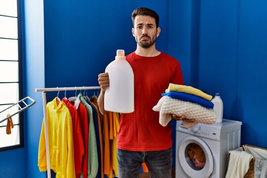Young hispanic man holding detergent bottle depressed and worry for distress, crying angry and afraid. sad expression.