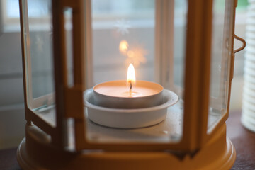 A small candle is burning inside a glass lamp