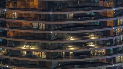 Outside view of windows in apartments of a high class building at night timelapse. Glowing lights in skyscraper. Chairs on balconies